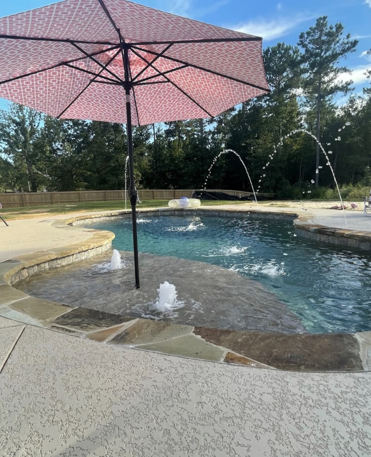 Pool with baja shelf tanning ledge, in-pool umbrella, and deck jets.