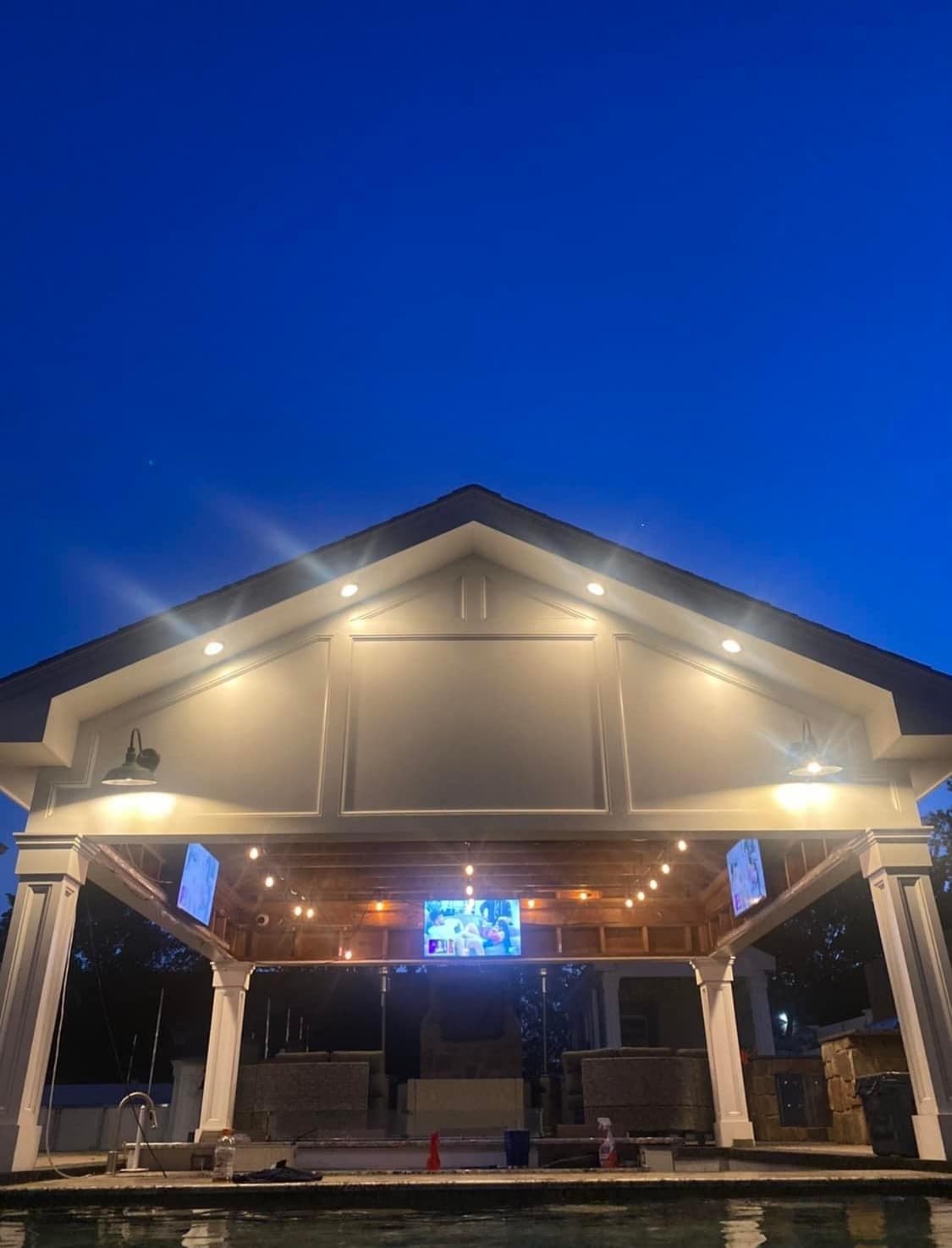 Covered outdoor living space with fireplace and pool views.