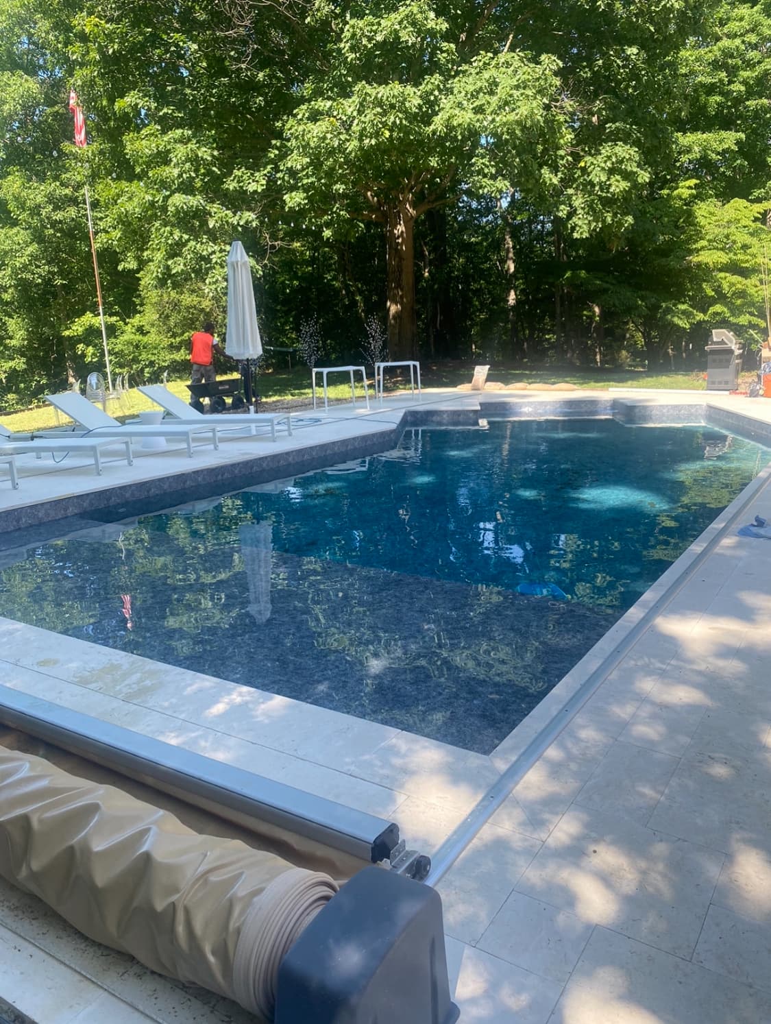 Crystal-clear rectangular pool with manicured stone deck and lounge area.