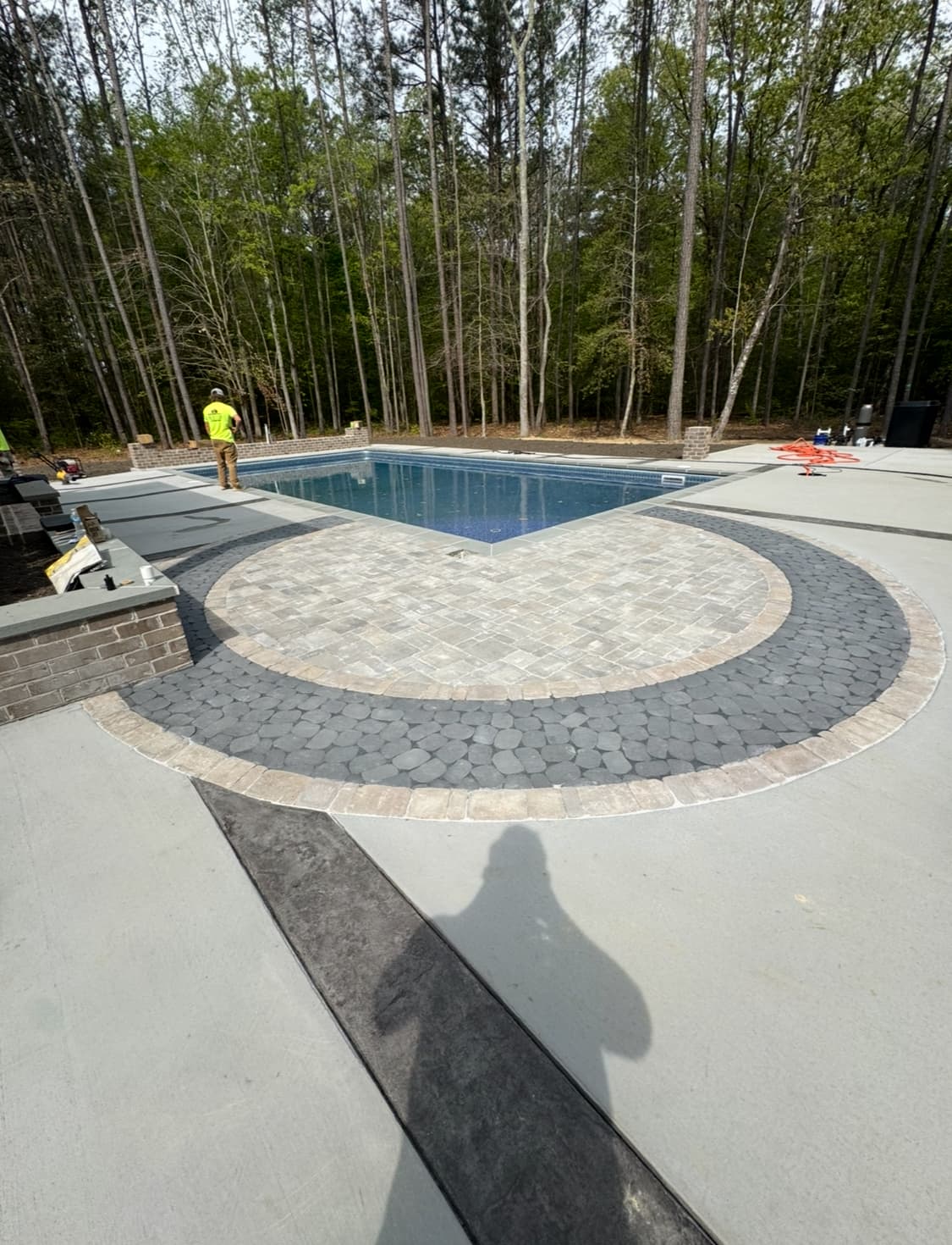 Decorative circular paver patio design surrounding a custom pool.