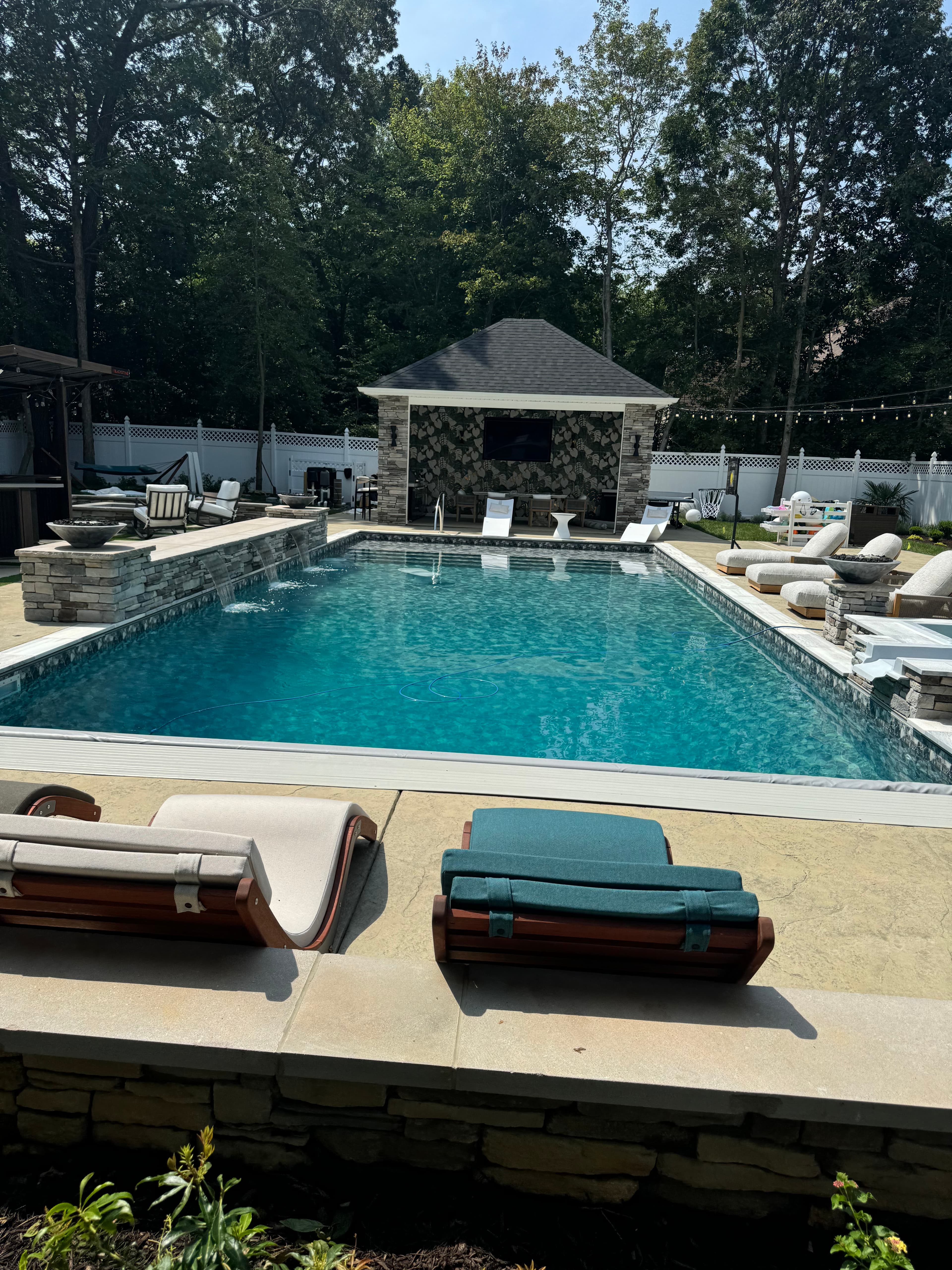 Stacked stone retaining walls defining levels around a custom pool.